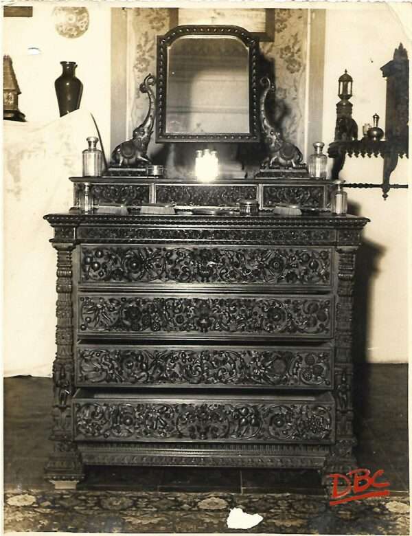 ENLARGE PHOTOGRAPH OF THE CHESTER DRAWER FACING CAMERA ON TOP OF IT IS A MIRROR SUPPORTED BY ELEPHANT