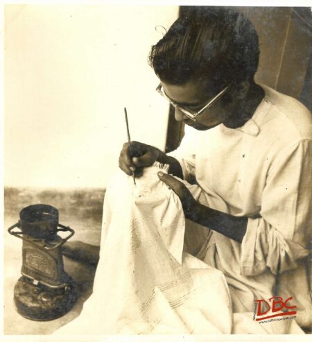 STUDENT FROM SANT IN IKETAM WORKING ON A PIECE OF COTTON CLOTH